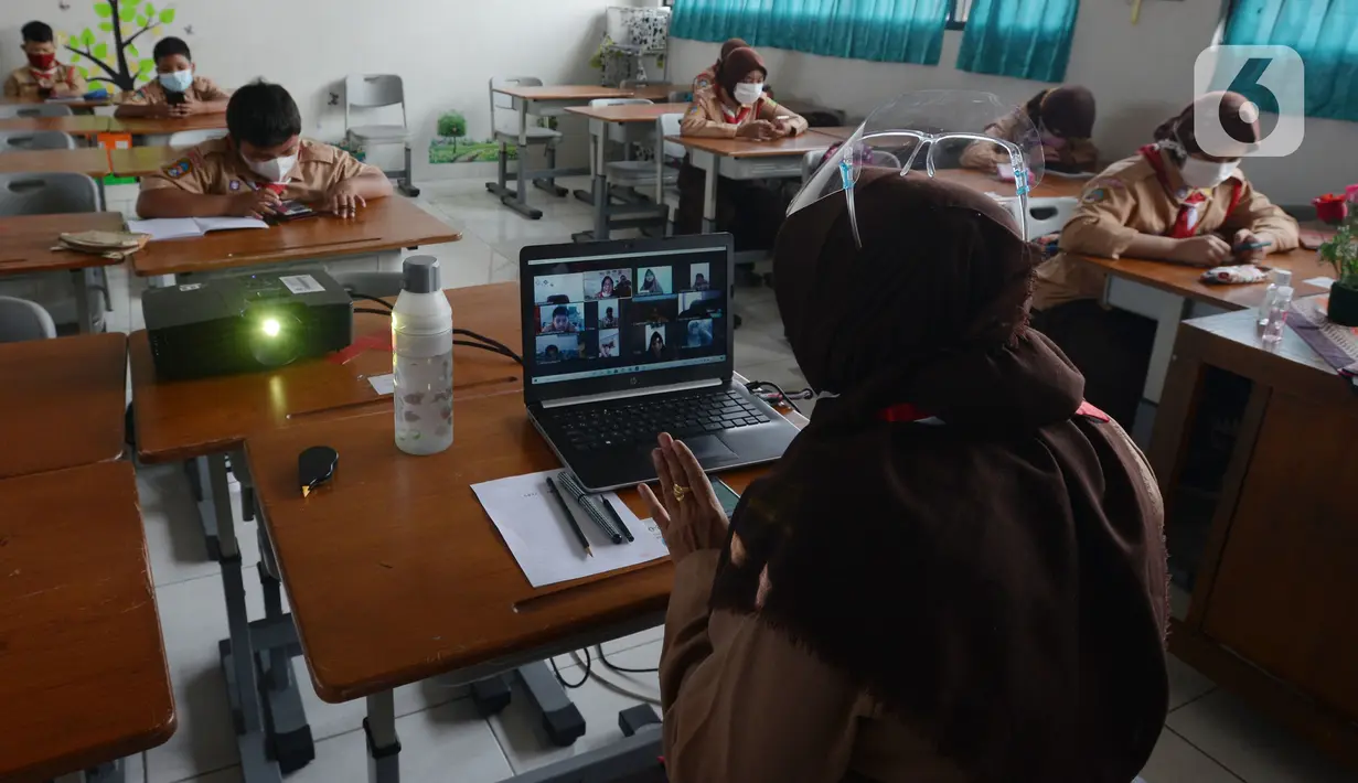 Guru mengajar para murid saat uji coba pembelajaran tatap muka di SDN Malaka Jaya 07 Jakarta, Rabu (9/6/2021). Pembelajaran dilakukan secara campuran antara online (daring) dan tatap muka langsung. (merdeka.com/Imam Buhori)