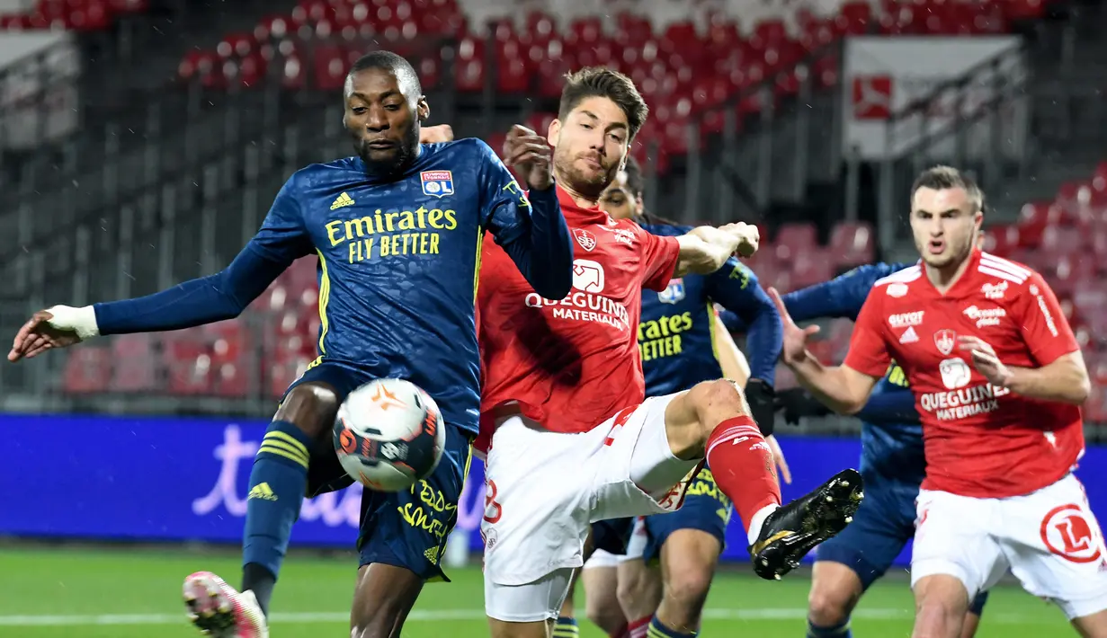 Striker Lyon, Karl Toko (kiri) melepaskan tendangan yang dihalangi gelandang Brest, Paul Lasne dalam laga lanjutan Liga Prancis 2020/21 pekan ke-26 di The Francis Le Ble Stadium, Brest, Jumat (19/2/2021). Lyon menang 3-2 atas Brest. (AFP/Fred Tanneau)
