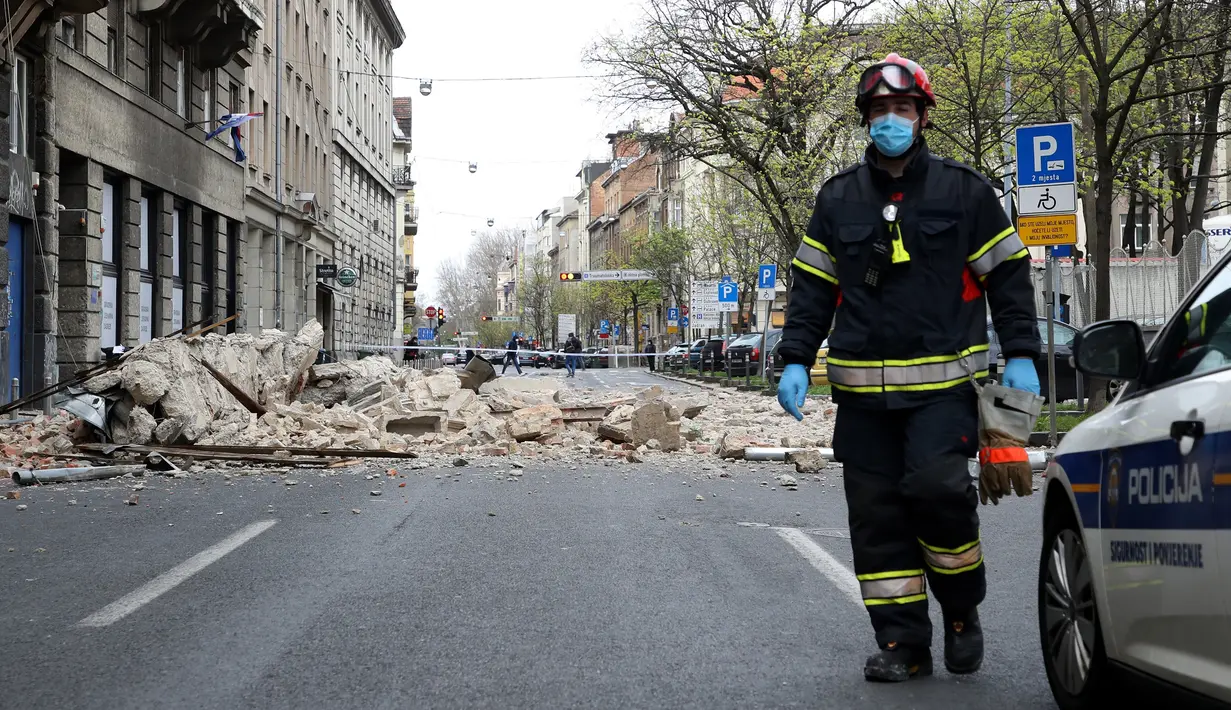 Seorang pemadam kebakaran Kroasia berjalan melewati puing-puing setelah gempa di jalan-jalan pusat kota Zagreb (22/3/2020). Lindu merusak sejumlah gedung dan membuat banyak mobil hancur karena terjangan batu. (AFP/Damir Sencar)