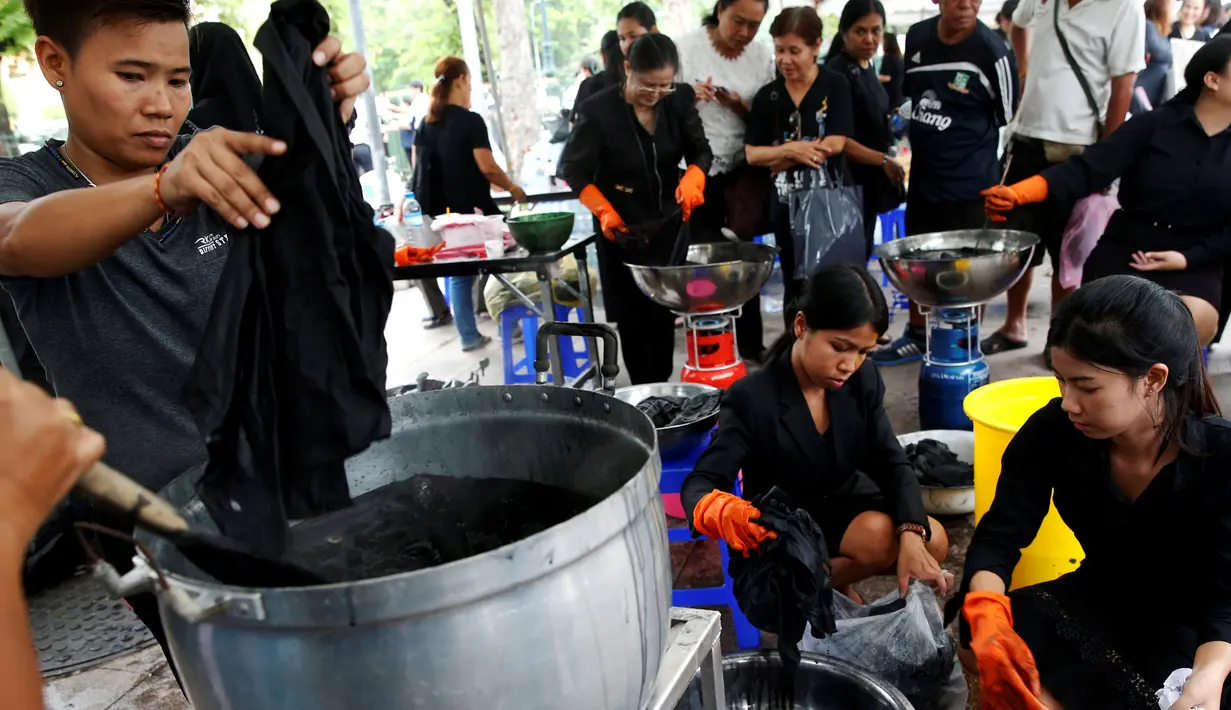 Relawan mewarnai pakaian pelayat agar menjadi hitam untuk dikenakan selama masa berkabung atas wafatnya raja Thailand Bhumibol Adulyadej di Grand Palace di Bangkok, Thailand (17/10). Relawan ini mewarnai pakaian warga secara suka rela.(Reuters/Edgar Su)
