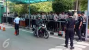 Pengendara motor melintas dekat sejumlah aparat kepolisian yang berjaga di pintu masuk Gedung MPR/DPR RI, Senayan, Jakarta, Jumat (31/3). Polda Metro Jaya memberikan pengamanan ketat di sekitar DPR terkait aksi 31 Maret. (Liputan6.com/Johan Tallo)