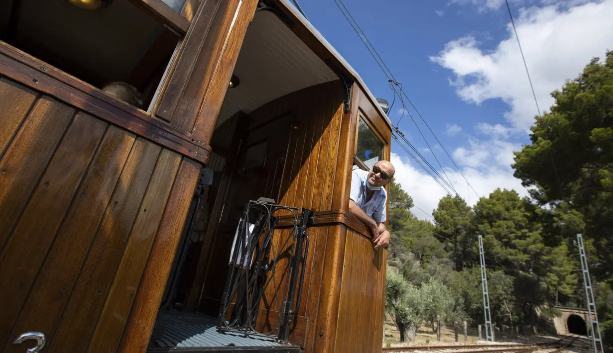 Kondektur Juan Marcus melihat ke luar jendela kereta Palma-Soller sebelum memulai perjalanannya di Palma de Mallorca di Kepulauan Balearic Spanyol (14/7/2021). (AFP/Jaime Reina)