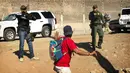 Seorang migran Amerika Tengah dihentikan agen AS yang memerintahkannya untuk kembali ke sisi perbatasan Meksiko, setelah sekelompok migran berhasil melewati polisi Meksiko di persimpangan Chaparral di Tijuana, Meksiko, (25/11). (AP Photo/Pedro Acosta)