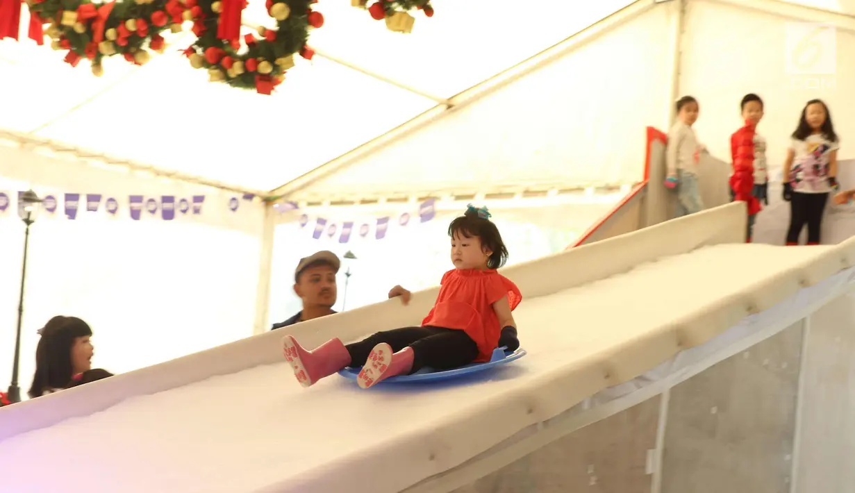 Seorang anak berseluncur di perosotan es di Lippo Mal Puri, Jakarta, Jumat (22/12). Jelang Natal banyak pusat perbelanjaan mendekor bangunannya bernuansa natal untuk menarik daya tarik minat masyarakat. (Liputan6.com/Angga yuniar)