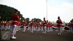 Aksi marching band Paspampres memainkan alat musik trompet dan baritone horn di halaman luar Istana Merdeka, Jakarta, Minggu (28/8). Pergantian pasukan jaga Istana Kepresidenan menjadi objek atraksi wisata baru bagi warga. (Liputan6.com/Faizal Fanani)