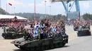 Warga bersama prajurit TNI berada di atas tank saat mengikuti defile pasukan dan kendaraan tempur pada peringatan HUT ke-72 TNI di Dermaga Indah Kiat, Cilegon, Kamis (5/10). HUT kali ini mengambil tema "Bersama Rakyat TNI Kuat" (Liputan6.com/Angga Yuniar)