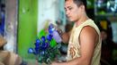 Seorang pekerja menyemprot bunga mawar agar terlihat lebih menarik di pasar bunga di Manila, Filipina, Senin (13/2/2023). Buket tersebut merupakan bagian dari gimmick Hari Kasih Sayang oleh seorang pemilik toko bunga. (AP Photo/Aaron Favila)