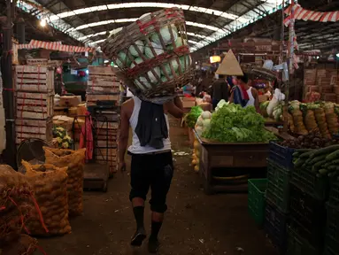 Seorang buruh berjalan mengangkut kerajang sayur di kawasan Pasar Induk Kramat Jati, Jakarta, Sabtu (14/01). Sempitnya lapangan pekerjaan dan pendidikan yang minim membuat mereka nekat untuk mengadu nasib sebagai buruh angkut. (Liputan6.com/JohanTallo)