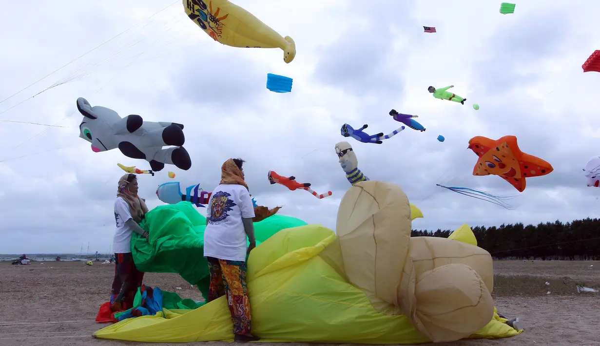 Wanita Indonesia menyiapkan layang-layang mereka untuk diterbangkan saat festival layang-layang di Bali, Indonesia, (4/8). Festival ini diselenggarakan untuk mempromosikan pariwisata di pulau resor. (AP Photo/Firdia Lisnawati)