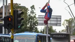 Seorang pria Kolombia bernama Jahn Fredy Duque bergelantungan layaknya superhero Spiderman di jalanan Bogota, Kolombia, Senin (24/4). Duque mencari nafkah dengan melakukan atraksi layaknya Spiderman. (AFP Photo/RAUL ARBOLEDA)