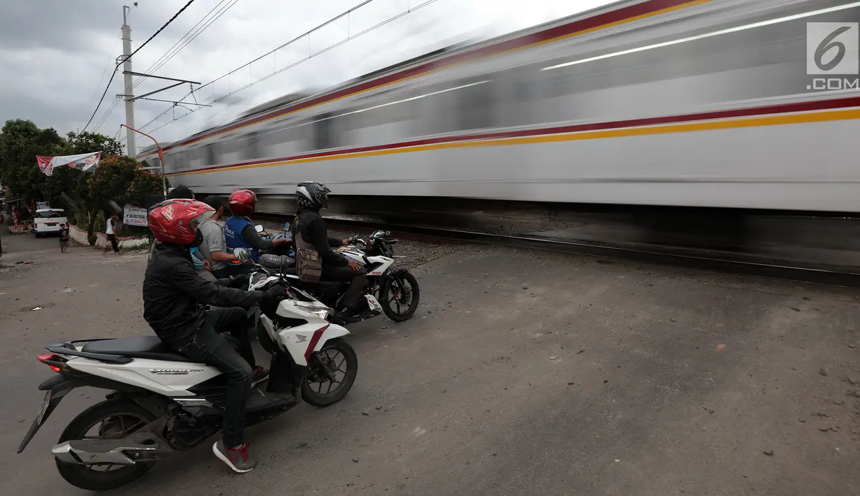 Pengendara sepeda motor menghentikan kendaraannya saat sebuah kereta api melintas di perlintasan kereta api tanpa palang pintu di kawasan Kelingkit, Rawa Buaya, Jakarta Barat, Selasa (26/2). (Liputan6.com/Johan Tallo)