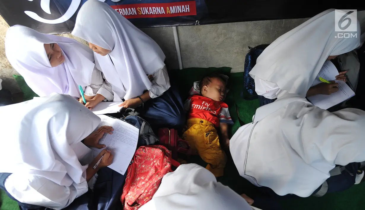 Seorang anak tidur saat siswa kelas 8 SMP 1 Cijeruk Terbuka belajar di halaman rumah warga di Kampung Cijeruk RT 002/005, Bogor, Jawa Barat, Senin (2/9/2019). Para siswa belajar di halaman depan dan belakang rumah warga setelah sebelumnya menumpang di gedung madrasah. (merdeka.com/Arie Basuki)