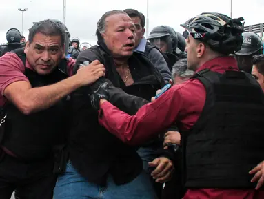 Menteri Keamanan Provinsi Buenos Aires Sergio Berni (tengah) diselamatkan dari protes di Buenos Aires, Argentina, Senin (3/4/2023). Berni dihajar sekelompok sopir bus yang tengah berdemo. (Andres Pelozo/AFP)