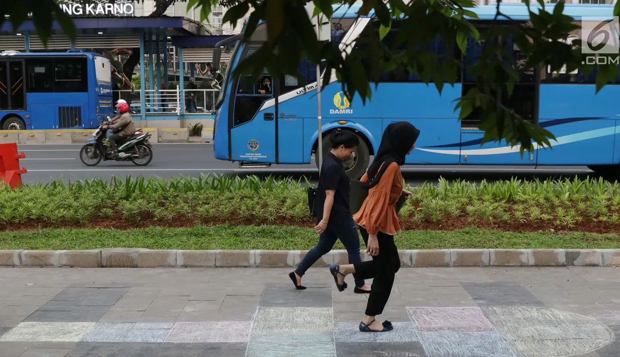 Pejalan kaki bermain permainan anak engkle di trotoar sekitar Halte Gelora Bung Karno, Jakarta, Jumat (17/5/2019). Koalisi Pejalan Kaki melakukan eksperimen permainan untuk mengedukasi kegiatan mengembalikan fungsi trotoar lebih dari sekedar ruang berjalan kaki. (Liputan6.com/Helmi Fithriansyah)