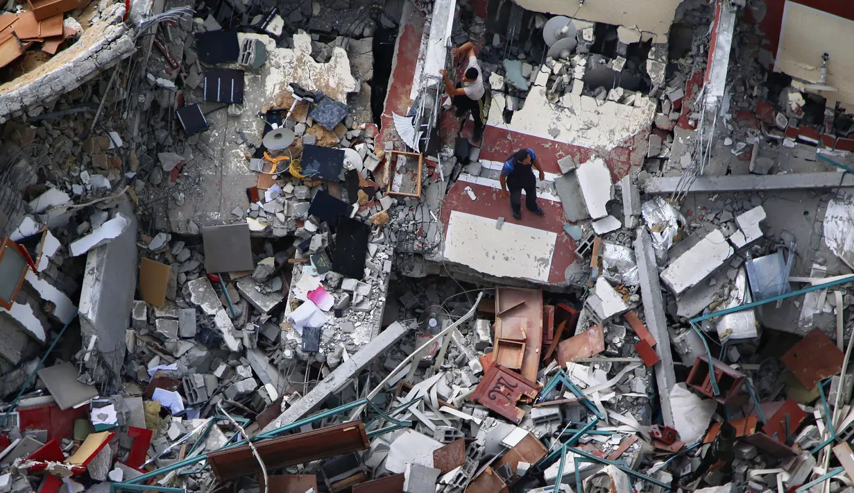 <p>Warga Palestina memeriksa bangunan hancur yang menampung kantor The Associated Press dan media lainnya, setelah terkena serangan udara Israel pekan lalu, di Kota Gaza, Jumat (21/5/2021). Israel dan Hamas telah sepakat untuk gencatan senjata setelah 11 hari pertempuran. (AP Photo/Hatem Moussa)</p>