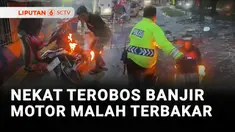 Ada sepeda motor terbakar setelah nekat menerobos banjir di Jalan Raya Daan Mogot, Cengkareng, Jakarta Barat. Untuk memadamkan api, seorang polisi mendorong sepeda motor dan menceburkannya ke jalan yang terendam banjir.