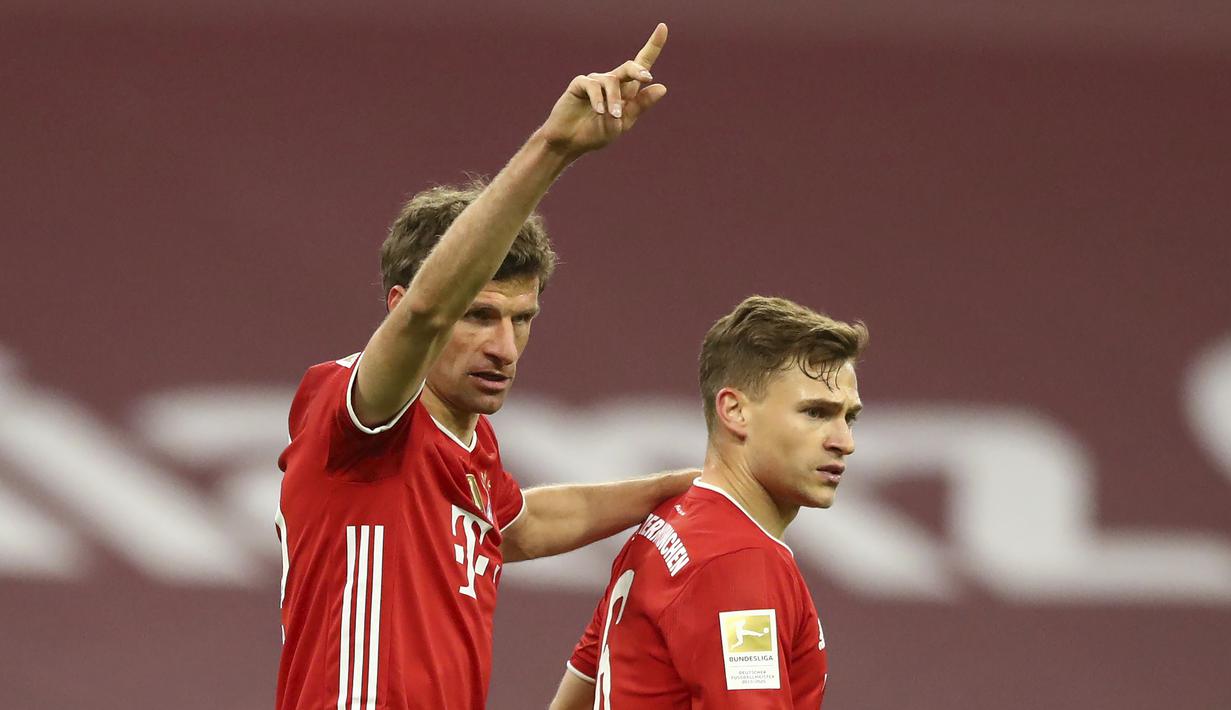 Striker Bayern Munich, Thomas Mueller (kiri) merayakan gol kedua timnya yang dicetak Joshua Kimmich (kanan) dalam laga lanjutan Liga Jerman 2020/2021 pekan ke-30 di Allianz Arena, Munich, Selasa (20/4/2021). Bayern Munich menang 2-0 atas Leverkusen. (AP/Matthias Schrader/Pool)