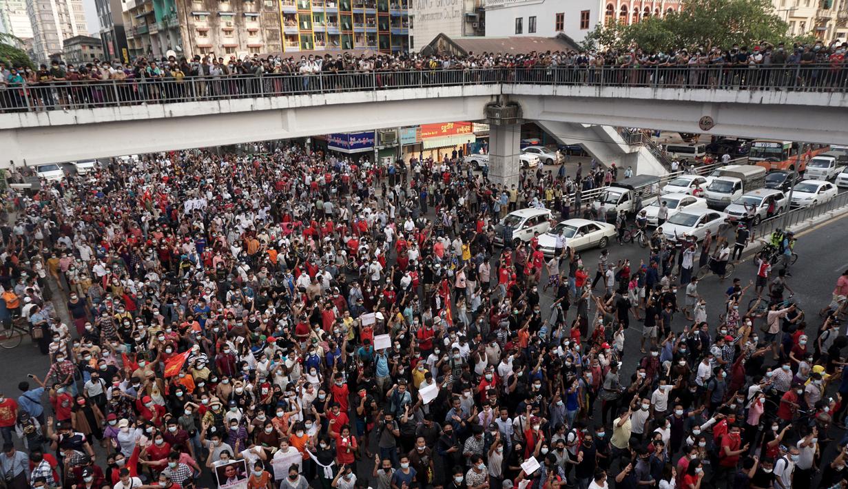 Para pengunjuk rasa berjalan di persimpangan jalan besar saat demonstrasi menentang kudeta militer di Yangon, Myanmar pada Sabtu (6/2/2021). Sebagian besar mengangkat tangan sambil menunjukkan simbol tiga jari yang melambangkan perlawanan terhadap pengambilalihan oleh militer. (STR / AFP)
