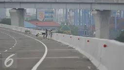 Pekerja menyelesaikan pekerjaannya di jalan tol akses pelabuhan Tanjung Priok, Jakarta, Jumat (27/5). Ditargetkan jalan tol ini selesai pada Maret 2017. (Liputan6.com/Gempur M Surya)