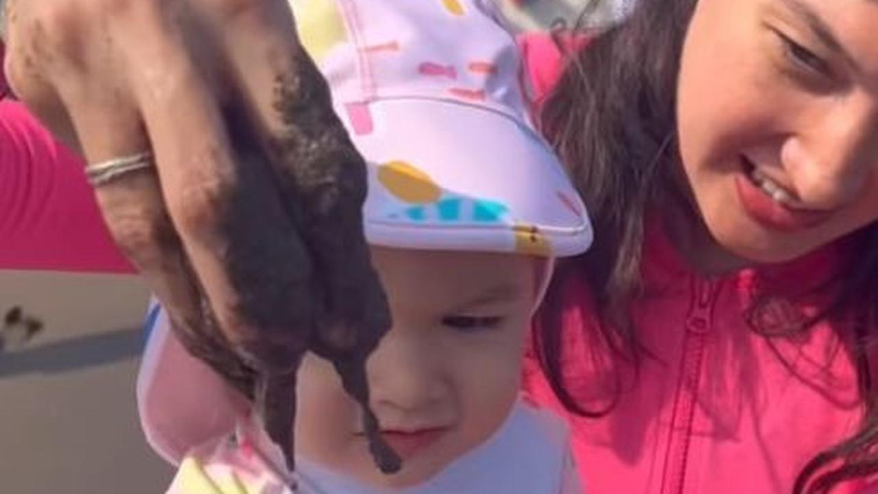 Nadine Chandrawinata ikut bermain pasir bersama sang anak. Dia menggenggam pasir pantai dan ditunjukan kepada Baby Djiwa.