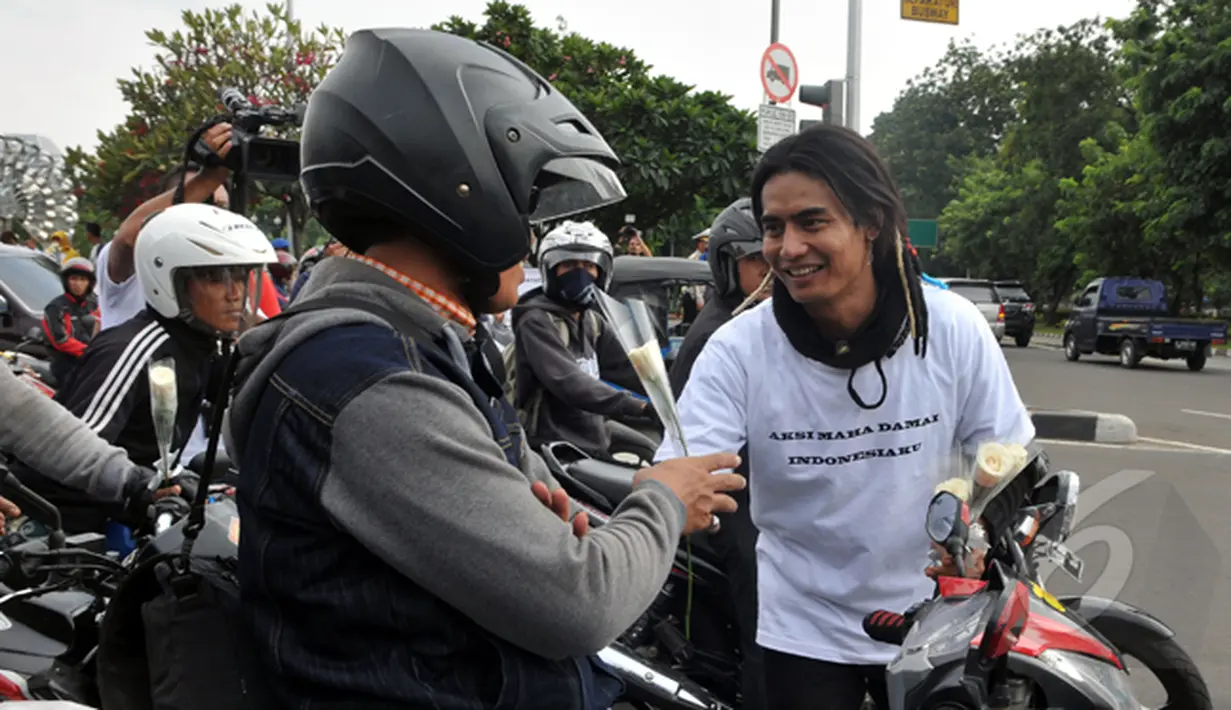 Charli memberikan bunga kepada para pengendara saat 'Aksi Maha Damai' di depan Istana Negara terkait kasus KPK vs Polri bersama Komunitas Anak Bangsa, Jakarta, Selasa (3/2/2015). (Liputan6.com/Panji Diksana)