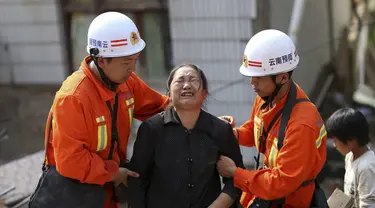 Petugas penyelamat membantu seorang wanita yang menangis di zona gempa di Longtoushan, provinsi Yunan, Tiongkok, (6/8/2014). (REUTERS/Stringer)