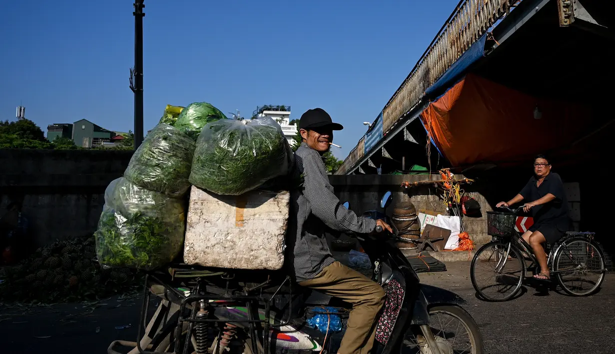 Seorang pedagang membawa sayuran di pasar grosir di Hanoi (26/8/2020). (AFP Photo/Manan Vatsyayana)