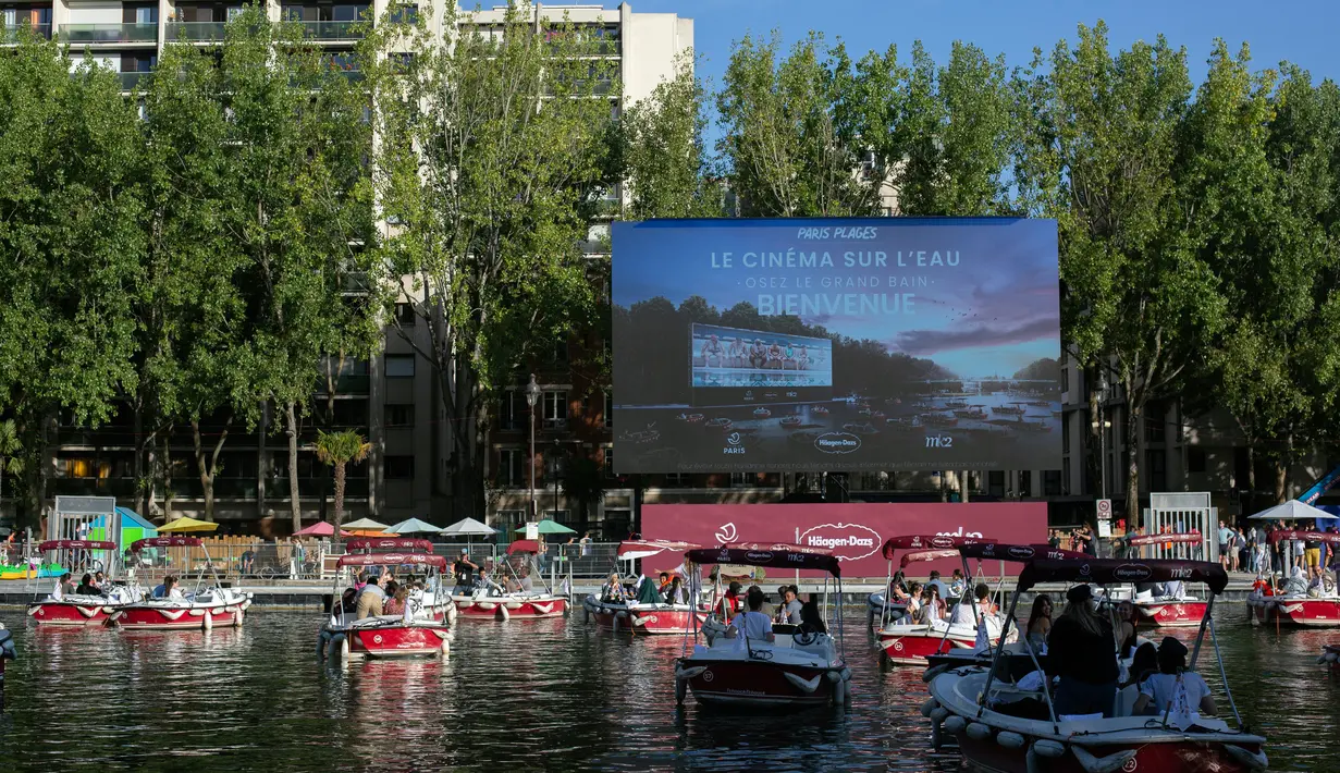 Orang-orang di atas kapal menghadiri Cinema on the Water, yang diselenggarakan Paris Plages selama pemutaran "Le Grand Bain" di Paris, Prancis pada 18 Juli 2020. Paris menghadirkan terobosan baru dengan bioskop terapung lengkap dengan perahu yang tetap menjaga jarak. (AP Photo/Rafael Yaghobzadeh)