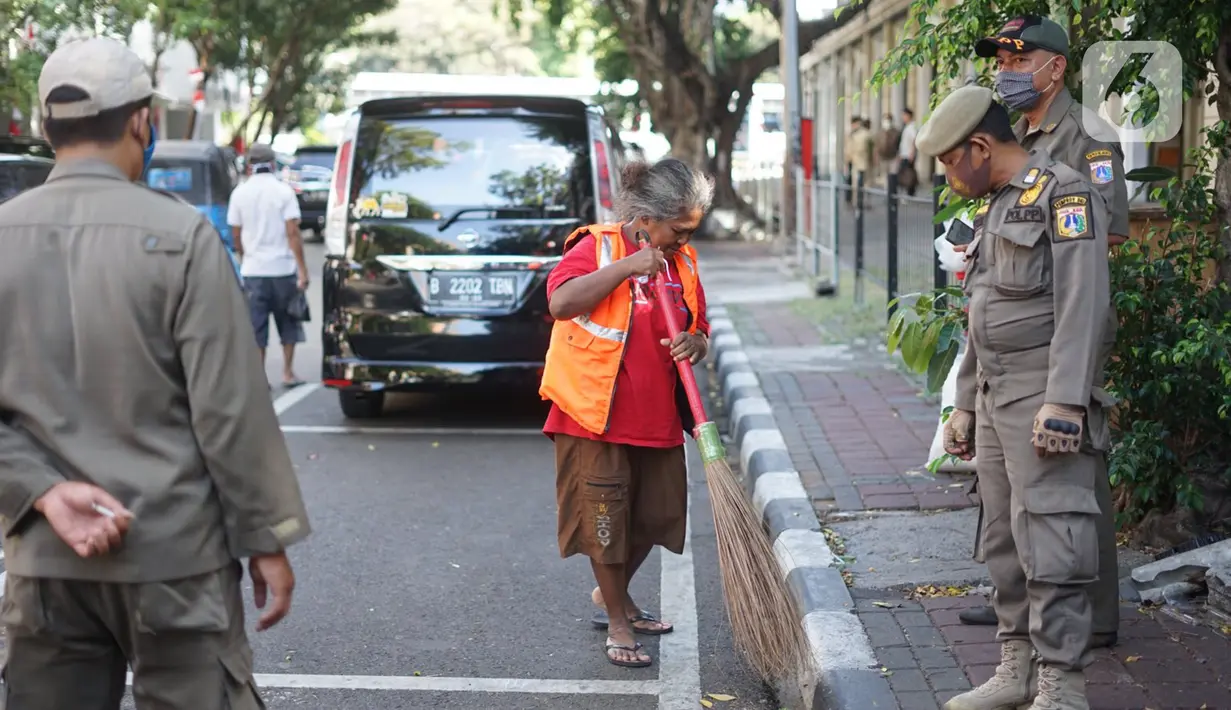 Petugas Satpol PP memberikan sanksi menyapu kepada warga yang tidak menggunakan masker di kawasan Pasar Baru, Jakarta, Jumat (21/8/2020). Sanksi tersebut dilakukan sebagai bagian dari upaya pencehagan penyebaran virus covid-19. (Liputan6.com/Immanuel Antonius)
