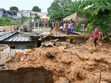 Warga melihat tempat di mana tim penyelamat mencari korban setelah rumah runtuh setelah hujan lebat di distrik Attecoube di Abidja, Pantai Gading (16/6/2022). Enam orang tewas semalam setelah hujan lebat memicu tanah longsor di ibu kota ekonomi Pantai Gading Abidjan, kata layanan darurat. (AFP/Issouf Sanogo)
