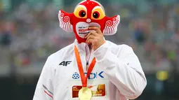 Atlet Polandia, Piotr Malachowski, menutup wajahnya dengan maskot Kejuaraan Dunia Atletik 2015 setelah meraih emas lempar lembing putra di Stadion Nasional, Beijing, Tiongkok. Minggu (30/8/2015). (Reuters/Damir Sagolj)