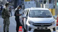 Polisi memeriksa penumpang di kendaraan pada hari pertama Perintah Kontrol Gerakan Penuh (MCO) di Kuala Lumpur, Malaysia (1/6/2021). Penguncian kedua dilakukan untuk mengatasi pandemi yang memburuk yang telah menempatkan sistem perawatan kesehatannya di ambang kehancuran. (AP Photo/Vincent Thian)