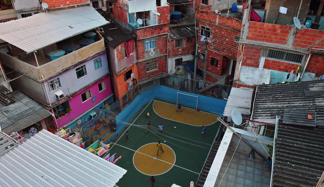 Lapangan kecil di lingkungan Tavares Bastos favela di Rio de Janeiro, Brasil mempunyai daya tarik tersendiri. Bagaimana tidak, lokasi yang sering digunakan untuk syuting film Hollywood tersebut dikelilingi oleh rumah padat penduduk. (AFP/Carl de Souza)