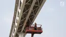 Pekerja menyelesaikan pembangun jembatan Skybridge di Ramangun, Jakarta, Kamis (4/7/2019). Pembangunan Skybridge sudah 98 persen rampung, yang nantinya akan menghubungkan Stasiun Kereta LRT Velodrome dengan halte busway Pemuda Rawamangun akan rampung akhir bulan ini. (Liputan6.com/Faizal Fanani)