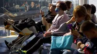 Para pelancong yang mengenakan masker menunggu penerbangan mereka di Bandara Internasional Hong Kong di Hong Kong, Selasa (21/1/2020). Masker terjual habis dan pemeriksaan suhu di bandara dan stasiun kereta api menjadi norma baru di China menyusul merebaknya wabah virus corona.  (AP/Ng Han Guan)