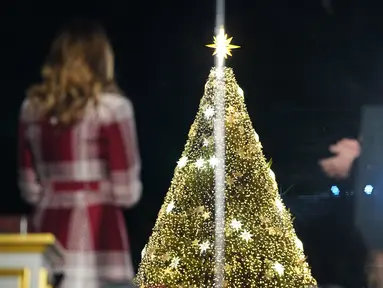 Presiden AS Donald Trump dan Ibu Negara Melania Trump bertepuk tangan saat upacara penerangan pohon cemara, yang menjadi Pohon Natal Nasional di taman sebelah selatan Gedung Putih, Kamis (5/12/2019). Pohon cemara setinggi 30 kaki tersebut dihiasi 50.000 lampu dan 450 bintang. (MANDEL NGAN / AFP)