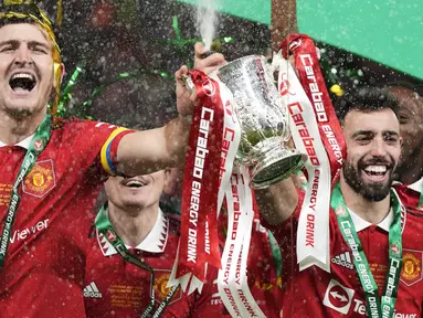 Pemain Manchester United, Harry Maguire (kiri) dan Bruno Fernandes mengangkat trofi bersama-sama setelah memenangkan final Carabao Cup 2023 melawan Newcastle United yang berlangsung di Wembley Stadium, Minggu (26/2/2023) waktu setempat. (AP Photo/Alastair Grant)