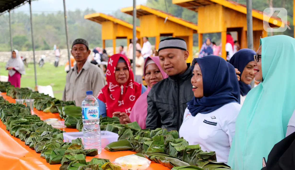 Warga melihat bungkus nasi kuning selama Gebyar Safar 1441 H di Desa Pangi, Kecamatan Suwawa Timur, Kabupaten Bone Bolango (Bonebol), Rabu (23/10/2019). Sebanyak 5.000 bungkus nasi kuning disajikan dalam perayaan yang turut dihadiri Bupati Bone Bolango, Hamim Pou, itu. (Liputan6.com/Arfandi Ibrahim)