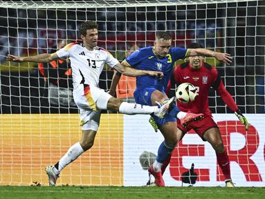 Penyerang Jerman, Thomas Muller berebut bola melawan bek Ukraina Oleksandr Swatok (tengah) dan kiper Anatolij Trubin dalam laga uji coba jelang Piala Eropa 2024 di Stadion Max Morlock, Nurenberg, Selasa (4/6/2024). (Tom Weller/dpa via AP)