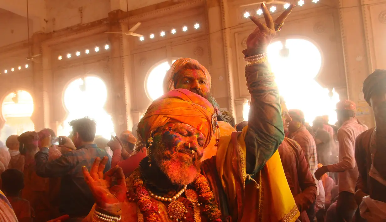 Umat Hindu menari saat bubuk berwarna dilemparkan ke arah mereka di Ladali atau kuil Radha selama festival Lathmar holi di Barsana, India, Selasa (23/3/2021). Perayaan Lathmar Holi berlangsung dari 23 Maret hingga 29 Maret tahun ini. (AP Photo)
