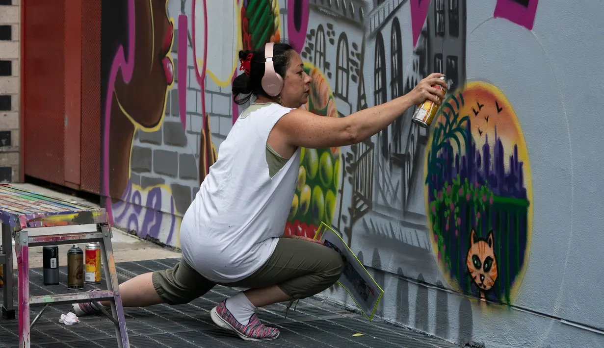 Seniman grafiti Sandra Fabara atau lebih dikenal Lady Pink melukis mural di Casita Maria, Bronx, New York, AS, Minggu (2/6/2019). Lady Pink dikenal juga dengan julukan 'The First Lady of Graffiti' atau 'Ibu Negara Grafiti'. (Don Emmert/AFP)