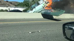Kendaraan melintas di dekat pesawat antik Amerika Utara AT-6 yang terbakar di US 101 di Agoura Hills, California (23/10). Kecelakaan menyebabkan kemacetan panjang sekitar 50 km di sebelah barat pusat kota Los Angeles. (AFP Photo/Cynthia Alvarez)