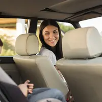 ibu memakaikan car seat untuk anaknya di mobil. credits: freepik