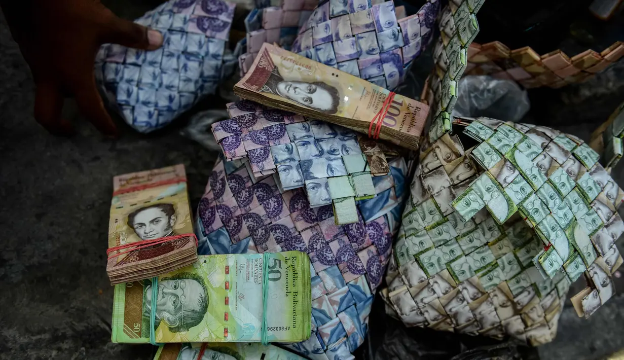 Wilmer Rojas (25) saat menjajakan kerajinan tangan dari lembaran mata uang Bolivar di Caracas, Venezuela, 30 Januari 2018. Dengan menggunakan jarum dan benang, Rojas menyulap lembaran Bolivar menjadi dompet hingga tas. (AFP Photo/Federico Parra)