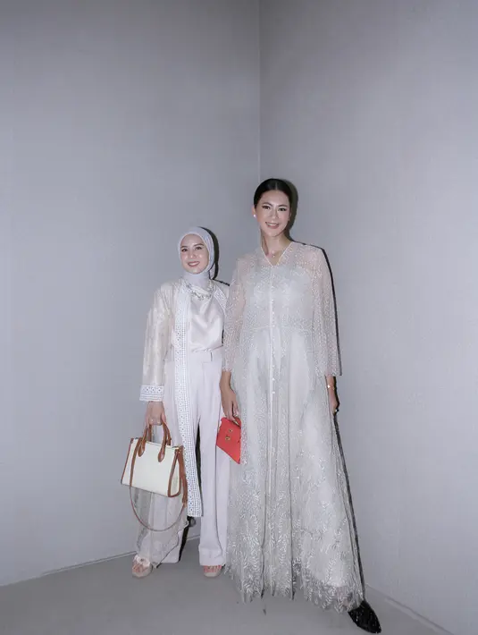 Paula Verhoeven berpose berdua dengan Tya Ariesta. Paula tampil dengan dress lengan panjang, sedangkan Tya memadukan atasan satin dengan celana panjang putih dan outer rancangan Sapto. [Foto: Document/FIMELA]
