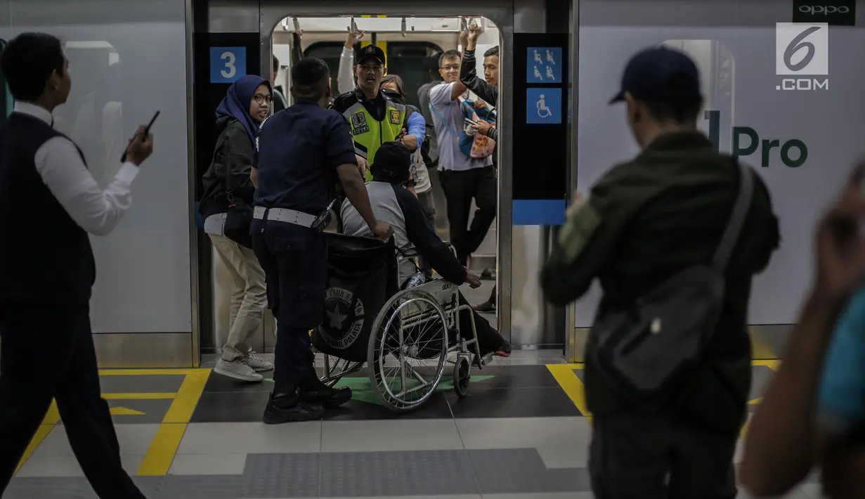 Petugas membantu penyandang disabilitas menaiki kereta MRT di pintu masuk Stasiun MRT Bundaran HI, Jakarta, Minggu (24/3). Moda Raya Terpadu (MRT) Jakarta Fase 1 dengan rute Bundaran HI - Lebak Bulus resmi beroperasi. (Liputan6.com/Faizal Fanani)