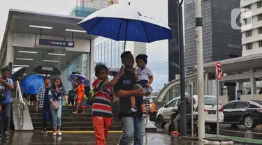 Seorang anak menawarkan jasa ojek payung di tengah hujan yang turun di kawasan Bundaran HI, Jakarta, Senin (3/2/2020). Hujan deras yang mengguyur sejumlah wilayah di DKI Jakarta dimanfaatkan para pengojek payung untuk mencari penghasilan tambahan. (Liputan6.com/Angga Yuniar)