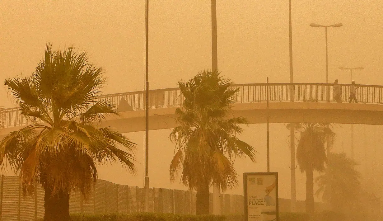 Warga berjalan di JPO saat terjangan badai pasir di Kuwait City, Kuwait, pada 17 Juni 2021. Terjangan badai pasir ini membuat jarak pandang atau visibilitas di beberapa daerah turun hingga kurang dari 100 meter. (AFP/YasserAl-Zayyat)