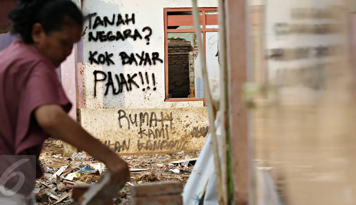 Sebuah tulisan terpampang di dinding rumah di bantaran Kali Ciliwung, Jakarta, Senin (11/1/2016). Jelang eksekusi yang akan dilakukan Pemprov DKI, warga mengambil  barang bangunan yang masih bisa dimanfaatkan kembali. (Liputan6.com/Immanuel Antonius)