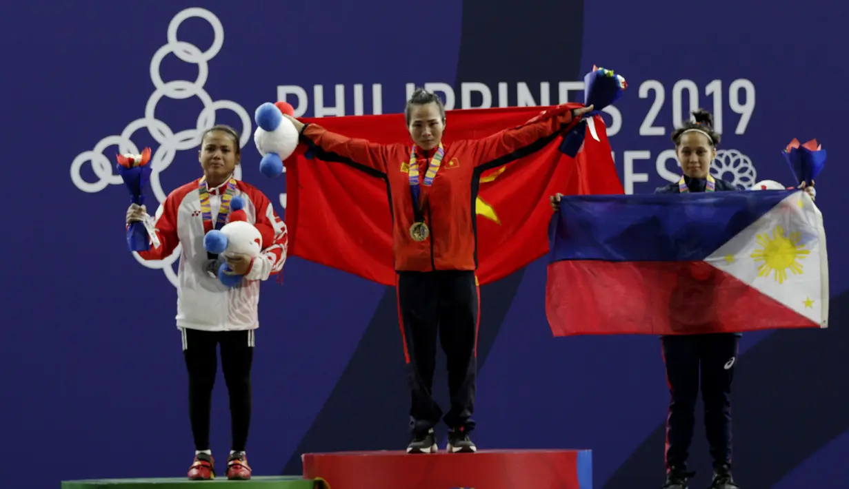 Lifter Lisa Setiawati (kiri) saat naik podium usai mendapatkan medali perak SEA Games 2019 cabang angkat besi nomor 45 kg di Stadion Rizal Memorial, Manila, Minggu (1/12). Dirinya meraih perak dengan total angkatan 169 kg. (Bola.com/M Iqbal Ichsan)